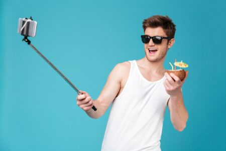 Fancy guy using his selfie stick to take a photo of a cocktail