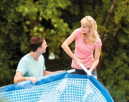 Couple installing an above ground swimming pool in their garden
